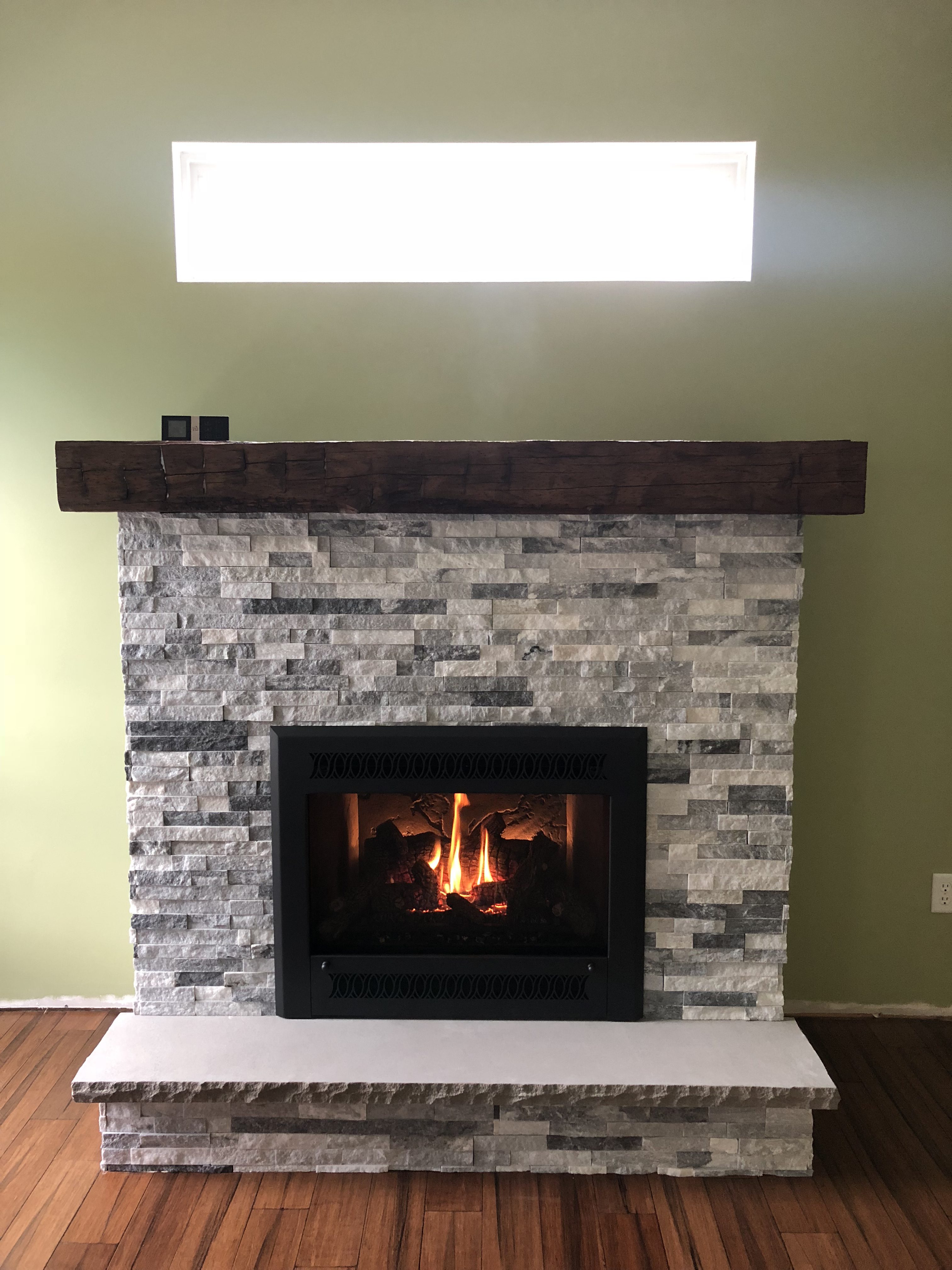 Image of a traditional 564 HighOutput gas fireplace by Fireplace X featuring rustic stonework facing and mantle.
